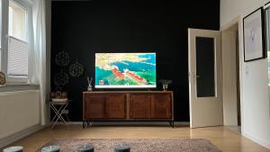 Elle comprend une télévision à écran plat installée au-dessus d'un meuble en bois. dans l'établissement Designerwohnung Afrika sehr zentral gelegen, à Hanovre