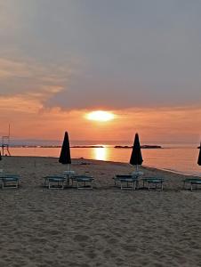 - un groupe de tables et de parasols sur une plage au coucher du soleil dans l'établissement Dimora il Trabucco, à Termoli