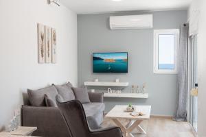 アギオス・ニコラオスにあるCasaDeMarのソファと壁掛けテレビのあるリビングルーム