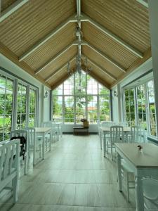 Cette chambre comprend des tables, des chaises blanches et des fenêtres. dans l'établissement Me and Tree Villa, à Kaeng Khoi
