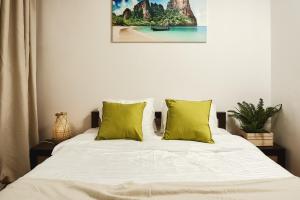 sypialnia z łóżkiem z zielonymi poduszkami w obiekcie Lumina spacious apartment near the railway station w Warszawie