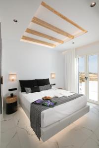 a white bedroom with a large bed and a window at Naxos White Concept in Naxos Chora