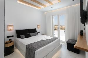 a white bedroom with a bed and a large window at Naxos White Concept in Naxos Chora