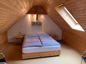 a bedroom with a bed in a attic with two tables at Gästehaus A+C Bovet in Wesenberg