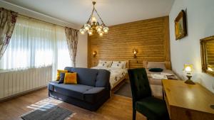 een slaapkamer met een bed, een bank en een stoel bij Zimski san in Ravna Gora