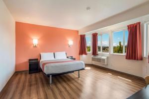 Motel 6-Rohnert Park, CA في رونيرت بارك: غرفة نوم مع سرير بجدران برتقالية ونوافذ
