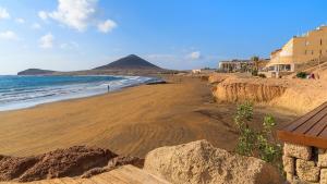 una playa con rocas y el océano y una montaña en Medano Nest Hostel, en El Médano