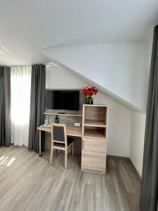 a room with a desk with a computer and a tv at Hotel Ocean in Norddeich