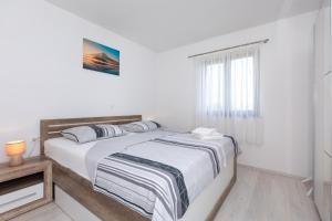 a white bedroom with a bed and a window at Apartments Otia Seaview in Porat