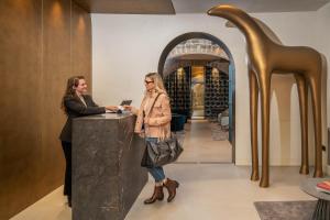 twee vrouwen aan een toonbank in een wijnwinkel bij PALAZZO UBERTINI Urban Suites in Viterbo