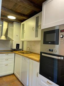 a kitchen with white cabinets and a stove top oven at Casa Rural MADRESELVA 2 in Navelgas