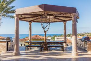 a pavilion with a table and benches and the ocean at The Residences at Hacienda Encantada in Cabo San Lucas