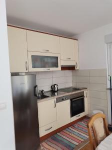 uma cozinha com armários brancos e um frigorífico de aço inoxidável em Apartman Marijana em Ljubuski