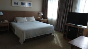サンパウロにあるA1 Flats Radisson Berriniのベッド1台、薄型テレビが備わるホテルルームです。