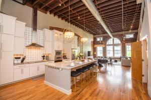 ノックスビルにあるLargest Rooftop w Firepit - Vaulted LUXE Penthouseの白いキャビネットと大きな島のある広いキッチンが備わります。