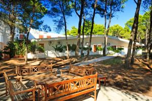 a group of wooden benches in a park with trees at Hotel Kyrie Isole Tremiti in San Domino