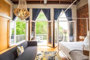 ノックスビルにあるLargest Rooftop w Firepit - Vaulted LUXE Penthouseのベッド1台、ソファ、窓が備わる客室です。