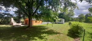 une maison dans un champ avec un arbre dans l'établissement Vacances a la campagne mobil home tout confort , chalet avec barbecue,, à Javron-Les-Chapelles