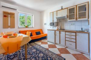 a kitchen and living room with an orange couch at Apartmani Jarić in Novi Vinodolski