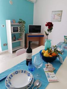 een tafel met een fles wijn en een fruitschaal bij Appartamento Il Gabbiano in Balestrate
