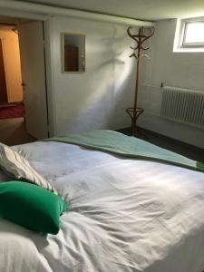 a large white bed with a green pillow on it at Doubleroom in basement w own bathroom in Rörum, Österlen in Simrishamn