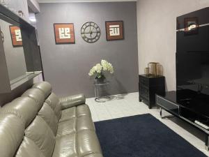 a living room with a leather couch and a television at Homestay Permai Inn in Temerloh