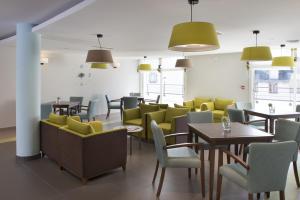 a restaurant with tables and chairs and yellow chairs at Domitys La Fleur de Lin in Landerneau