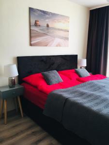 Un dormitorio con una cama roja con una pintura en la pared en apartmán MONYA, en Turčianske Teplice