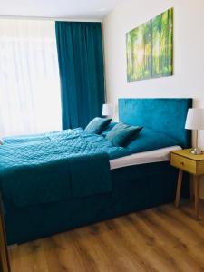 1 dormitorio con cama con sábanas azules y ventana en apartmán MONYA, en Turčianske Teplice