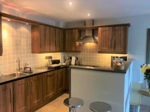 a kitchen with wooden cabinets and a sink and stools at Ardhowen Bay lakefront holiday accommodation in Enniskillen