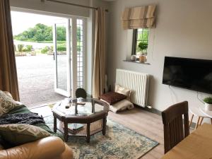a living room with a couch and a table and a tv at Ardhowen Bay lakefront holiday accommodation in Enniskillen