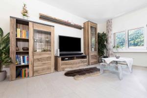 a living room with a flat screen tv and wooden entertainment centers at Bärghäsli im BEO als Basis im Wintersportgebiet in Gsteigwiler