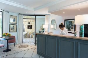 a woman standing at a bar in a salon at Hôtel La Grande Bastide in Saint-Paul-de-Vence