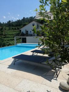 una piscina con 2 tumbonas junto a una casa en Casa de Caneiro, en Cabeceiras de Basto