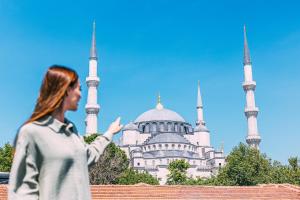 une femme debout devant un bâtiment comprenant deux mosquées dans l'établissement RW BOUTIQUE HOTEL, à Istanbul