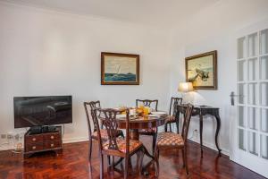 a dining room with a table and chairs and a television at Charming TM Flat by the Ocean with a View in Cruz Quebrada