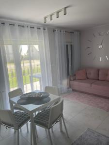 a living room with a table and chairs and a clock at Apartament Luxor in Niechorze