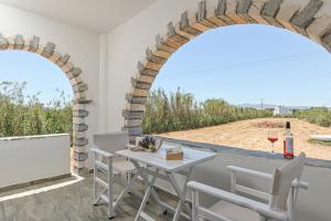 um pátio com 2 arcos, uma mesa e cadeiras em Vive Mare Plaka II em Naxos Chora