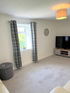 ein Wohnzimmer mit einem TV und einem Fenster in der Unterkunft Cosy retreat in beautiful Cornwall in Helston