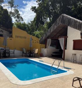 a pool at a resort with tables and chairs at Pousada Arraial Colonial in Arraial d'Ajuda