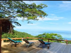 eine Terrasse mit Stühlen und Meerblick in der Unterkunft L'Auberge Polynésienne in Tevaitoa