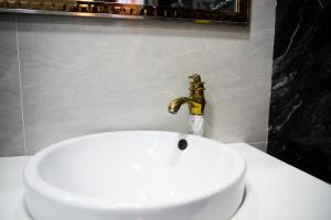 um lavatório branco com uma torneira dourada na casa de banho em Bonuluxhome em Samarkand