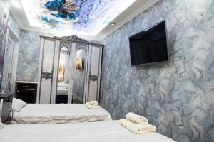 a bedroom with two beds and a tv on the wall at Bonuluxhome in Samarkand