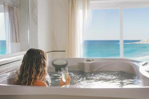 a woman sitting in a bath tub with a drink at Fistral Beach Hotel and Spa - Adults Only in Newquay