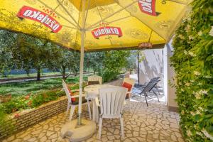 a patio with a table and chairs under a yellow umbrella at Apartments Hortensia in Pula