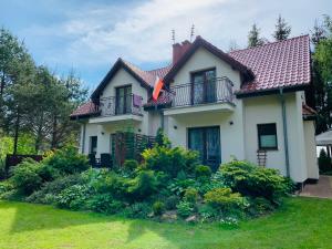 a white house with a red roof and some bushes at Dom nad jeziorem Mazury pomost segment 2 in Giżycko