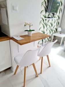 un tavolo e due sedie bianche in una stanza di Apartament LAKE z widokiem na jezioro a Ostróda
