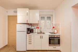 a white kitchen with white cabinets and appliances at Apartments Hortensia in Pula