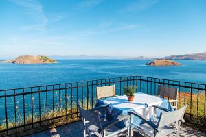 een tafel en stoelen op een balkon met uitzicht op het water bij Anaxos Hill in Anaxos