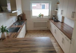 uma cozinha com armários brancos, um lavatório e uma janela em Inseltor em Niebüll